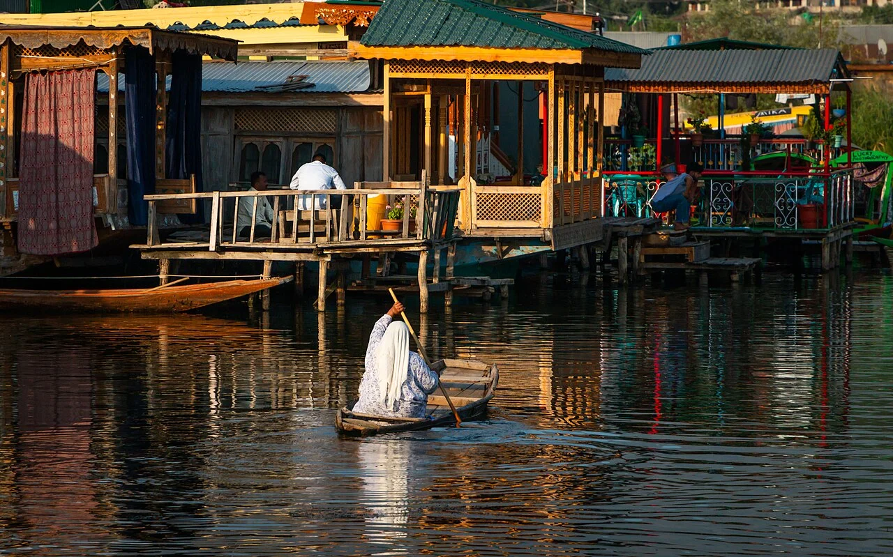 Carved wooden houseboats on Dal Lake with a shikara alongside