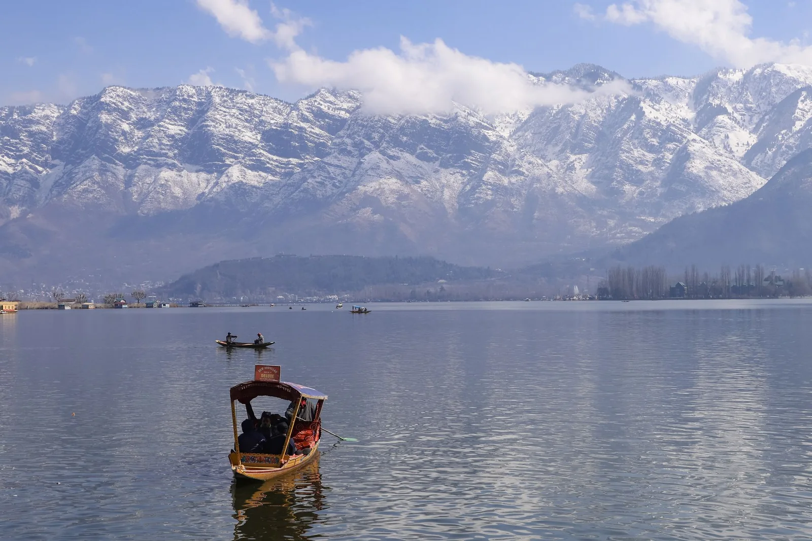 A shikara on Dal Lake beneath snow-covered mountains