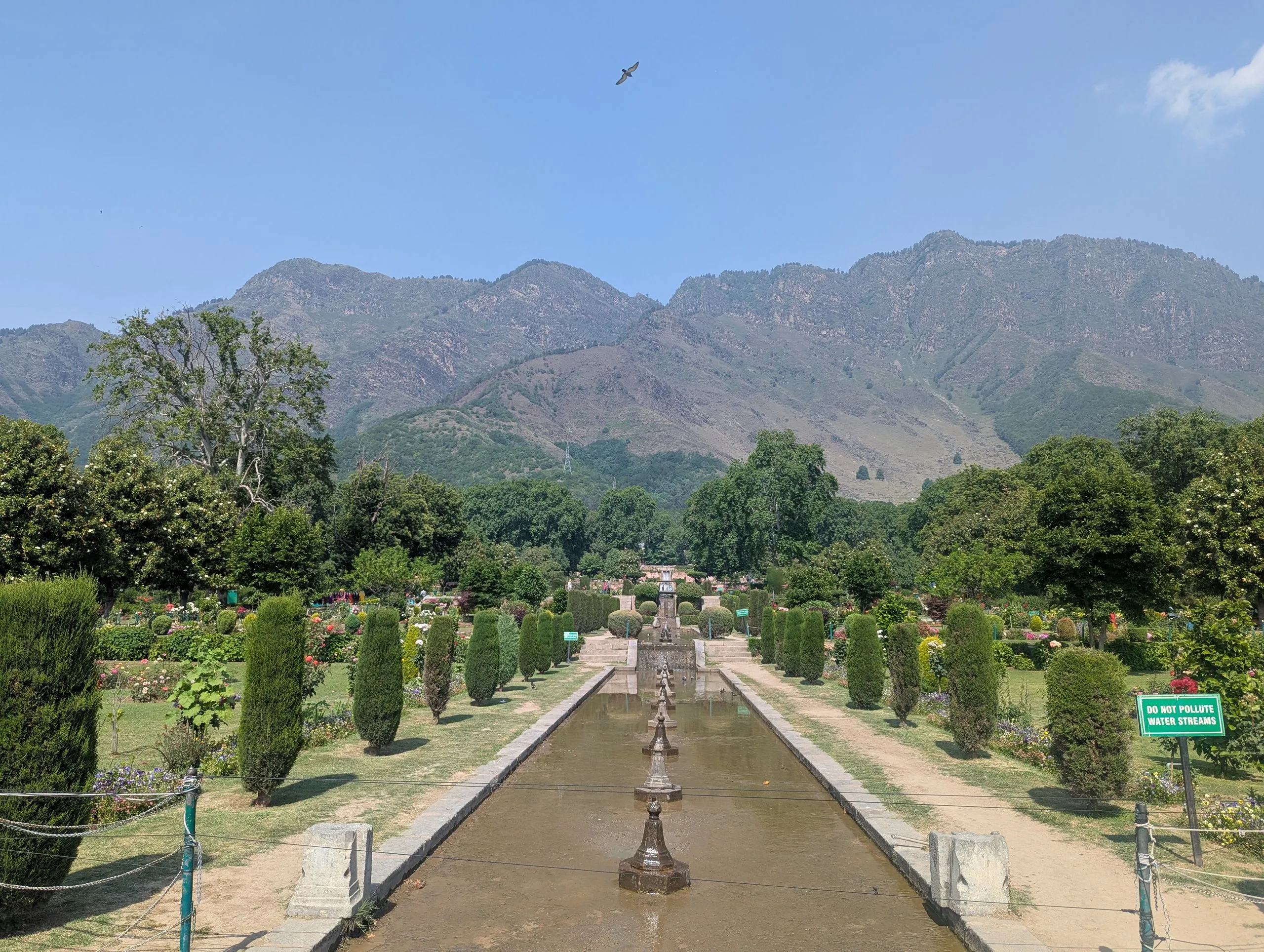 A Mughal garden water channel lined with fountains and cypress trees