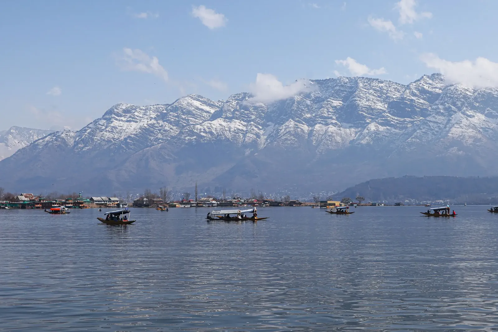 Shikaras and houseboats on Dal Lake below snow-covered mountains