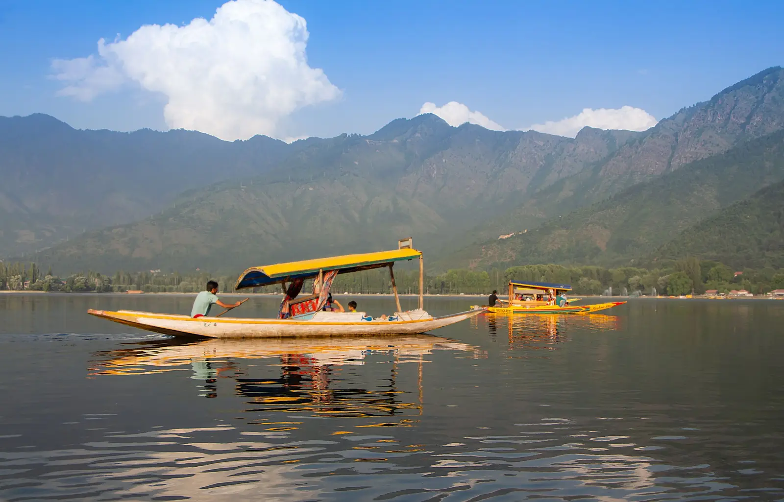 A shikara crossing Dal Lake beneath green hills