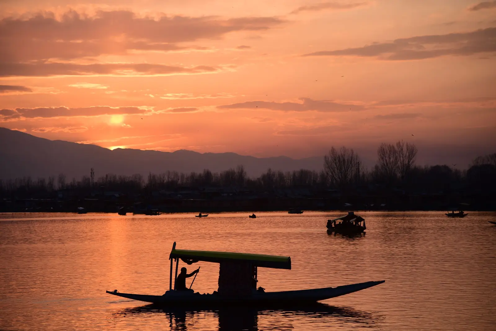 A shikara crossing Dal Lake at sunset